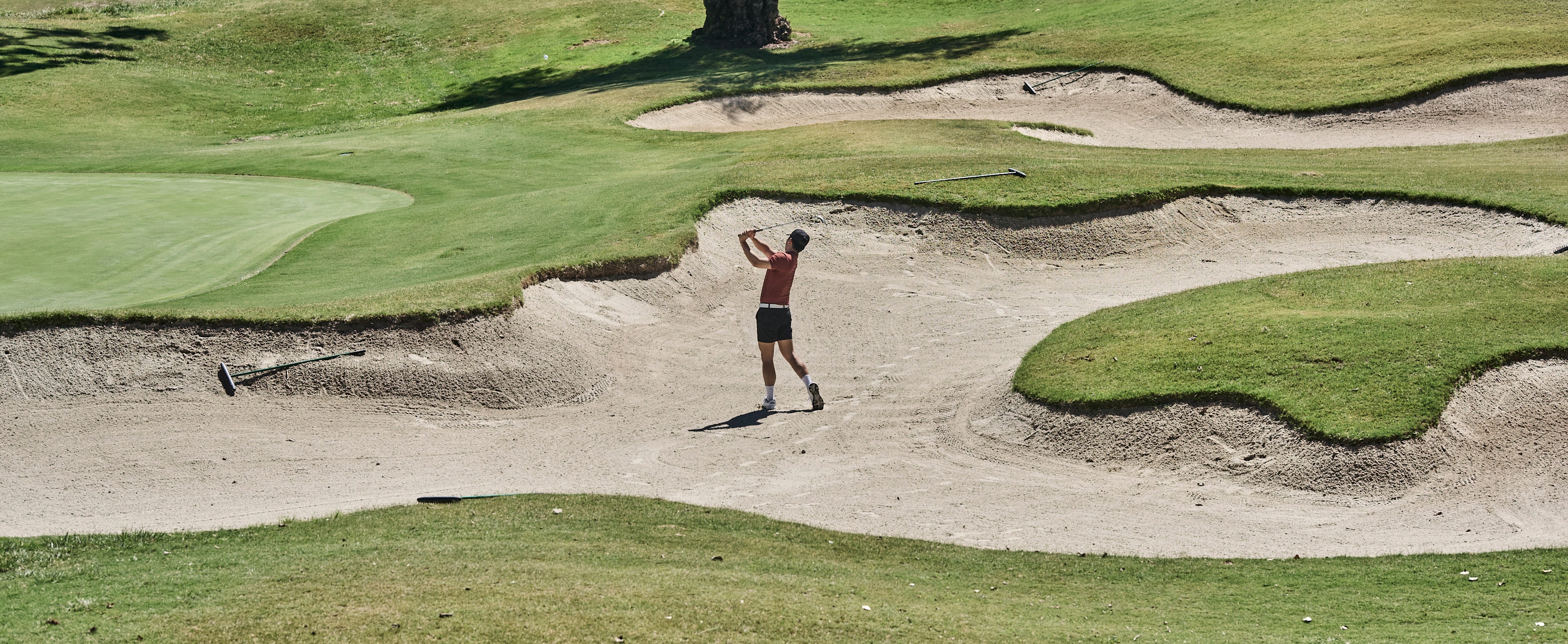Golf player hitting a ball from a sand trap on a golf course